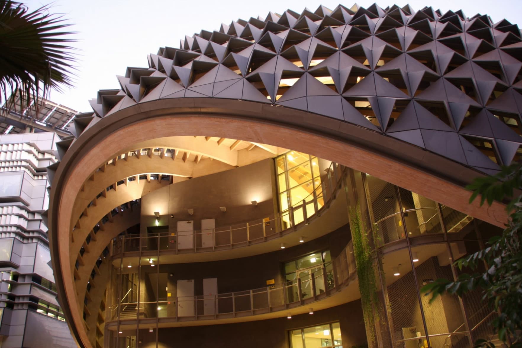 Curved building with a faceted metal shell over glazed balconies