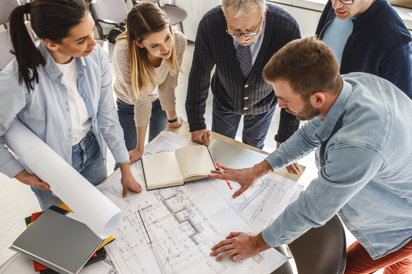 Architects and designers gathered around drawings on a table