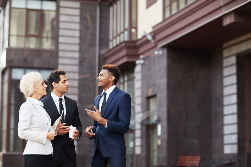 Real estate agents talking with a client outside an apartment building