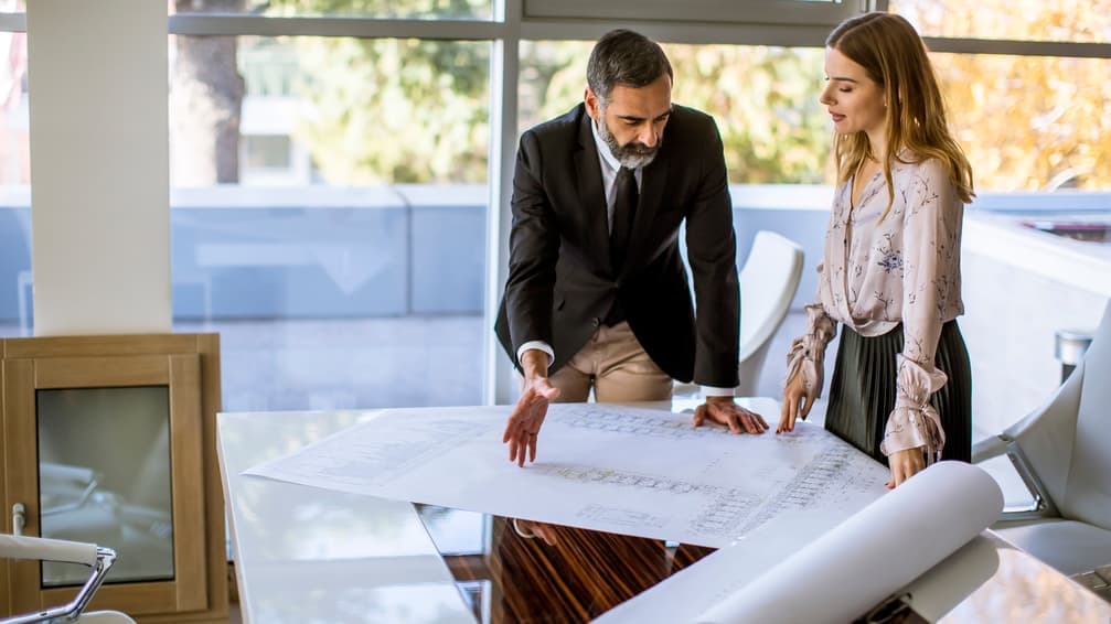 Two architects reviewing drawings by a window
