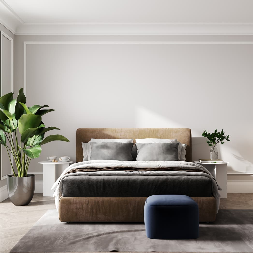 Bedroom with an upholstered bed, grey bedding and a velvet ottoman